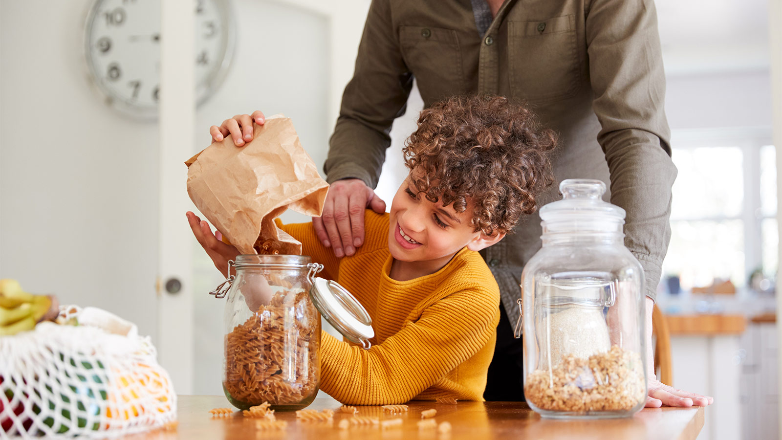 child filling pasta jar