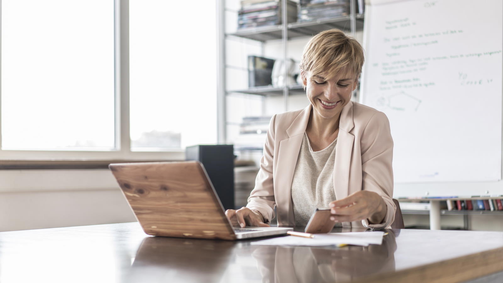 woman at desk on laptop and mobile